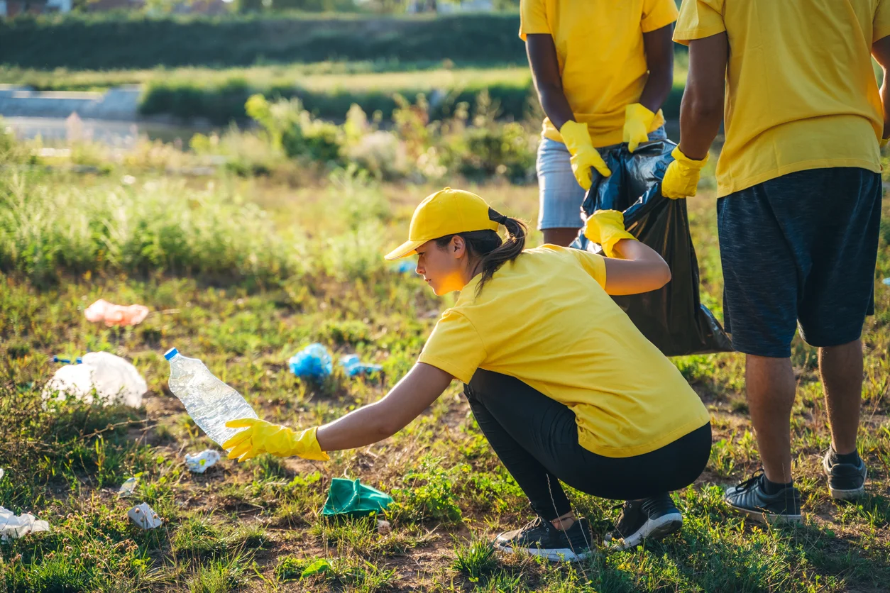 Young group of volunteers cleaning up garbage in nature.